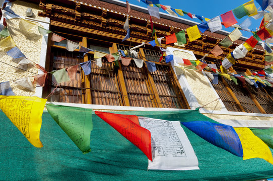 India, Jammu & Kashmir, Ladakh, prayer flags blowing in front of a traditional Ladakh building in downtown Alchi