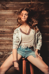 Beautiful brunette girl in short shorts posing in studio on wooden background.