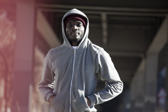 A hip young man standing under a city bridge in sports gear