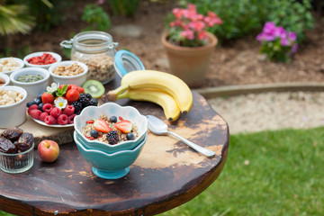 Paleo style breakfast served in the garden: gluten free grain free oat free granola with mixed nuts, and fresh berries and fruits, selective focus