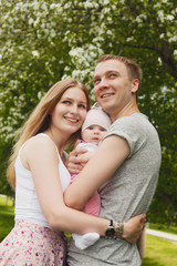 Fototapeta premium Young couple with newborn son outdoors in spring