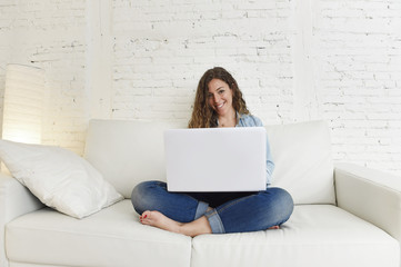Fototapeta premium young attractive spanish woman using laptop computer sitting relaxed working on home couch