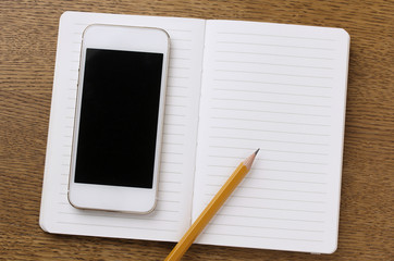 notebook and phone with blank screen on wooden table
