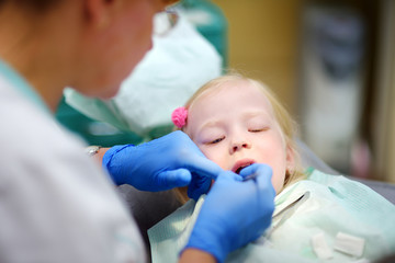 Little girl having her teeth examined by dentist