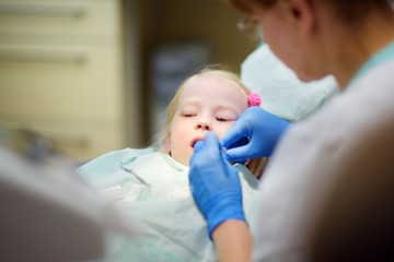 Little girl having her teeth examined by dentist