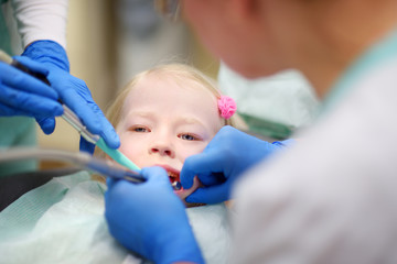 Little girl having her teeth examined by dentist