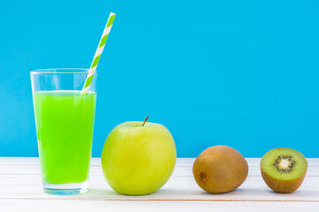 Fototapeta na wymiar Green smoothie with apple and kiwi on a white wooden table and blue background