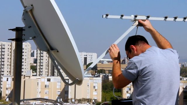 Technician installing  receiving device of satellite dish in the correct position with satellite  channels finder,