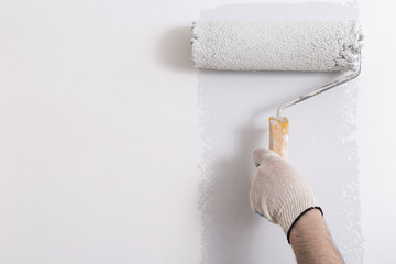 Close up of painter hand painting a wall grey with paint roller