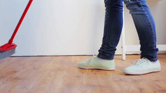 woman with broom cleaning floor at home