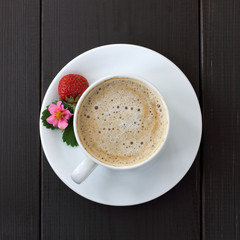 coffee break with strawberry aroma/ frothy coffee with decoration of berries, flower and leaf strawberries on a dark wooden background top view 