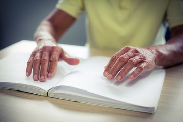 Senior blind man reading a braille book