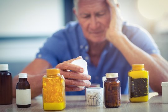 Senior man suffering from headache with prescription bottle
