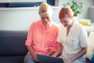 Fototapeta premium Female nurse and senior woman using laptop