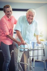 Senior woman helping senior man to walk with walker