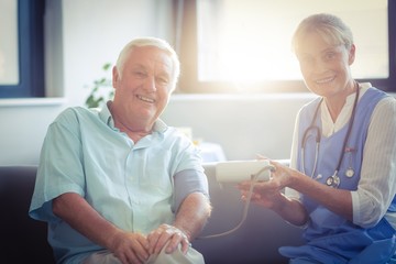 Obraz premium Female doctor checking blood pressure of senior man