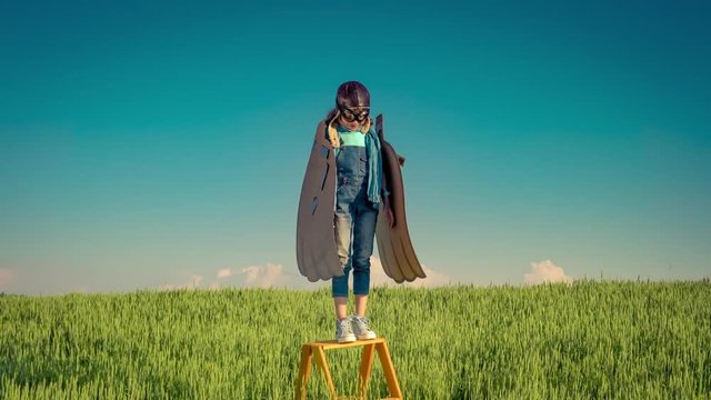 Happy kid playing with outdoors in summer field. Travel and vacation concept. Imagination and freedom