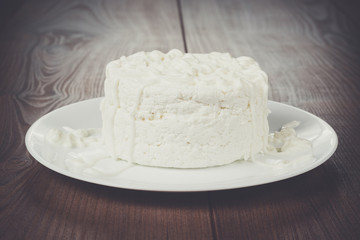 Cottage cheese in white plate on wooden table