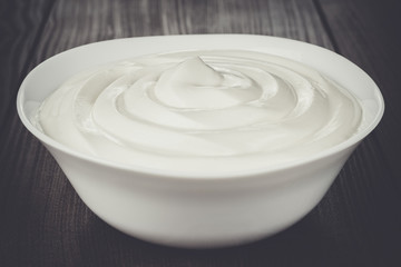 white bowl full of sour cream on wooden table