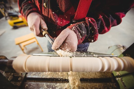 Fototapeta Close up carpenter sculpting wooden piece in workshop