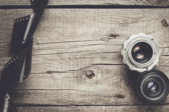 Retro Camera Lenses And Negative Film On Wooden Table