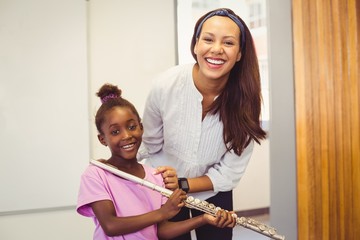 Portrait of teacher and girl with flute in classroom