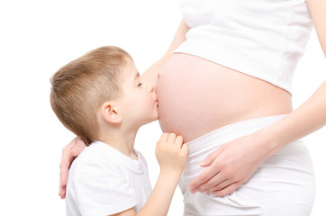 Cute boy kisses the belly pregnant mother