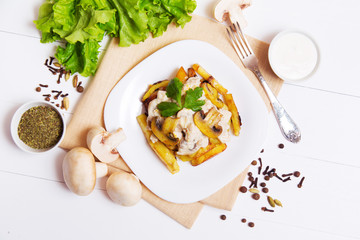 Fried potatoes with gravy of mushrooms in a plate on wooden background