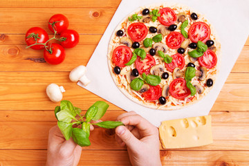 Prepared Italian pizza with sause, cheese and other  ingredients other on the wooden background 