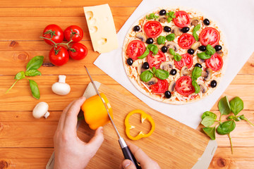Prepared Italian pizza with sause, cheese and other  ingredients other on the wooden background 