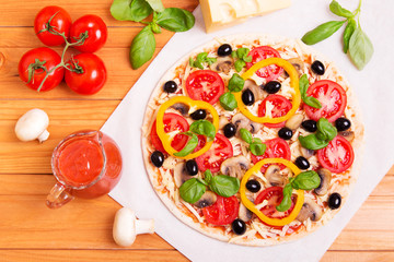 Prepared Italian pizza with sause, cheese and other  ingredients other on the wooden background 