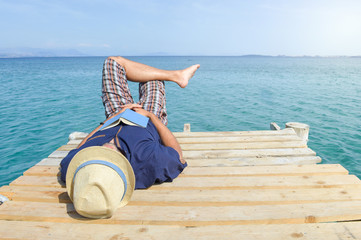 Man lying on the dock with a book