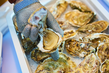 Fresh oyster held open with knife in hand