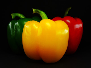 3 bright peppers on a black background: red, green, yellow
