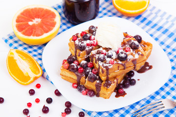 Delicious belgian waffles with berries, ice cream and chocolate sauce on a plate