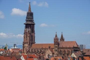 Ansicht des Freiburger M&uuml;nsters mit D&auml;chern der Stadt vor blauem Himmel