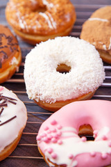 Colorful delicious donuts with coconut and other sprinkles on a dark wooden background