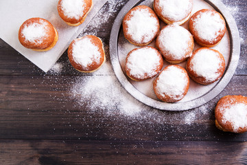 German donuts - berliner with jam and icing sugar in a tray on a wooden background. Top view - obrazy, fototapety, plakaty