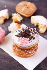 Colorful donuts with chocolate, glaze and sprinkles on a dark wooden background