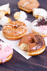 Colorful donuts with crumbs, glaze and sprinkles on a dark wooden table