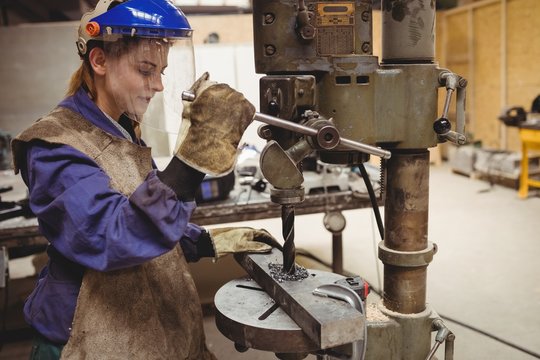 Female welder using a drill press