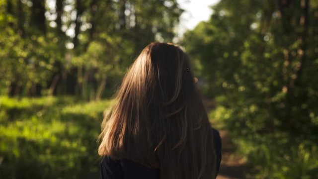 teen girl walking in park in sunset from behind shot with stabilizer