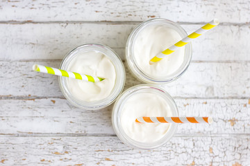 Yogurt in three small jars with straws