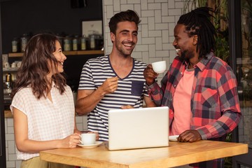 Friends interacting and laptop on the table