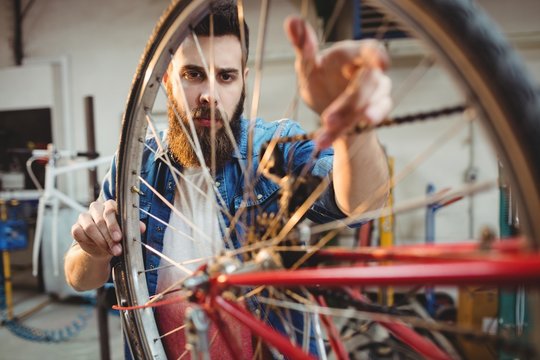 Portrait of a hipster repairing a bicycle wheel