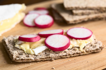 Wholemeal rye crispbread with brie cheese and radish slices, photographed with natural light...