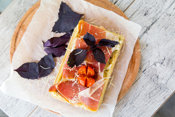 Belgian waffle with sauce, cured meat, Parmesan cheese, Basil and cherry tomatoes