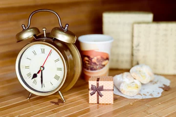 Fotobehang Closeup on set of alarm clock, gift box and dessert with hot drink © gorosi