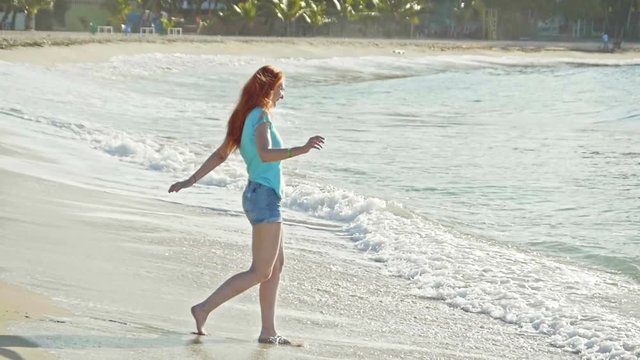 Young woman with long red hair play with waves running, feeling the sea, seascape, telephoto, slow-motion, beach of Dominican Republic,