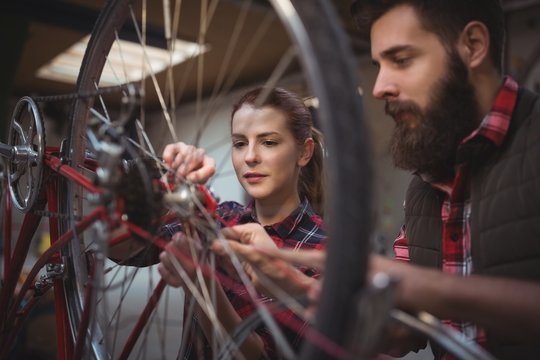 Mechanics repairing bicycle in workshop